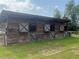 View of an older wooden barn with a metal roof and green lawn at 16850 Se 19Th Ct, Summerfield, FL 34491
