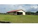 View of the barn on a lush green lawn with a partial red roof at 16850 Se 19Th Ct, Summerfield, FL 34491