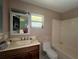 Bathroom with brown walls, wood vanity, beige-tiled backsplash, toilet, and bathtub with shower at 16850 Se 19Th Ct, Summerfield, FL 34491