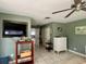 Bedroom with green walls, tile flooring, a television, white dresser, and access to other rooms at 16850 Se 19Th Ct, Summerfield, FL 34491