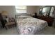 Bedroom with floral bedding, tile flooring, side chair, and dresser with ornate mirror at 16850 Se 19Th Ct, Summerfield, FL 34491