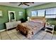 A bedroom with green walls, white tile flooring, and a decorated bed with white wood furnishings at 16850 Se 19Th Ct, Summerfield, FL 34491