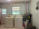 Functional laundry area featuring a washer, dryer, hot water tank and an exit door at 16850 Se 19Th Ct, Summerfield, FL 34491