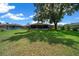 Home's beautiful backyard featuring lush green grass and mature tree provides a serene outdoor space at 21425 Sw Plantation St, Dunnellon, FL 34431
