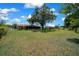 Spacious backyard features lush lawn, mature tree, chain link fence, and screened lanai in the home's design at 21425 Sw Plantation St, Dunnellon, FL 34431