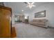 Bright living room with sliding doors to the outside patio, ceiling fan, and tan colored couch and carpet at 21425 Sw Plantation St, Dunnellon, FL 34431