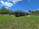 Expansive backyard featuring lush green grass, trees, and a cozy patio area at 235 Locust Pass Ln, Ocala, FL 34472