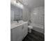 This bathroom has a tub with a shower, a single sink vanity, modern light fixtures, and a white tile surround at 235 Locust Pass Ln, Ocala, FL 34472