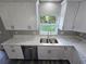 Well-lit kitchen featuring white cabinetry, stainless steel appliances, and a double sink beneath a window at 235 Locust Pass Ln, Ocala, FL 34472