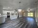 Open-plan living area showcasing wood floors, a kitchen island, and modern lighting at 235 Locust Pass Ln, Ocala, FL 34472