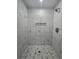 Detailed shot of modern, tiled shower with built-in shelf and hexagon tile floor at 235 Locust Pass Ln, Ocala, FL 34472