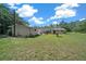 Wide backyard view featuring an additional building, patio area, and mature trees at 23737 Nw Mallard Ave, Dunnellon, FL 34431