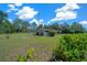 Well-kept single-story home with a lush lawn and mature trees, under a partly cloudy sky at 23737 Nw Mallard Ave, Dunnellon, FL 34431