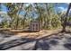 Exterior shot of shed featuring gray doors, gravel, and is surrounded by foliage at 3250 Sw 46Th Ave, Ocala, FL 34474