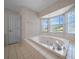 Bathroom with a large soaking tub, tiled surround, and a window with natural light at 5420 Sw 86Th Ln, Ocala, FL 34476