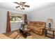 Cozy living room features a ceiling fan, a brown sofa and wood laminate flooring at 8443 Sw 109Th Place, Ocala, FL 34481