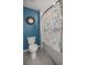 A bathroom with blue walls featuring a shower with ocean themed shower curtain and a toilet at 8617 Triumph Cir, Wildwood, FL 34785