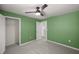 A bedroom with green walls, a ceiling fan, carpet flooring and access to both the closet and the hallway at 8617 Triumph Cir, Wildwood, FL 34785