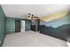 A spacious bedroom with an unique mural, carpet, modern ceiling fan, and connecting doors to other rooms at 8617 Triumph Cir, Wildwood, FL 34785