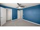 A bedroom with blue walls, a ceiling fan, carpet flooring and access to both the closet and the hallway at 8617 Triumph Cir, Wildwood, FL 34785