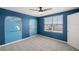 A bedroom with blue walls featuring a whimsical mural, ceiling fan, and a large window letting in natural light at 8617 Triumph Cir, Wildwood, FL 34785