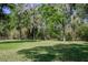 Large backyard features mature trees, lush green grass, and a chain link fence at 8950 Se 17Th Ct, Ocala, FL 34480