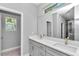 Bathroom with dual sinks, gray cabinets, large mirror and a window to let in natural light at 9405 Se 159Th Ln, Summerfield, FL 34491