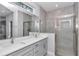 Modern bathroom with double vanity, large mirror and glass-enclosed tiled shower at 9405 Se 159Th Ln, Summerfield, FL 34491
