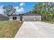 A modern single-story home featuring an attached two-car garage, stylish exterior, and well-kept lawn at 9405 Se 159Th Ln, Summerfield, FL 34491