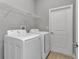 Bright laundry room with white washer and dryer and wire shelving above at 9405 Se 159Th Ln, Summerfield, FL 34491