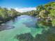 Aerial view captures the pristine turquoise waters winding through lush greenery and serene riverfront properties at 9525 Sw 200 Ct, Dunnellon, FL 34431