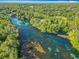 Aerial view showcases the river, bordered by lush greenery, with clear turquoise waters winding through the serene landscape at 9525 Sw 200 Ct, Dunnellon, FL 34431