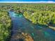 High-angle view showcasing a wide river lined by dense forests, with clear turquoise water running through the landscape at 9525 Sw 200 Ct, Dunnellon, FL 34431