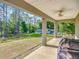 An outdoor covered back porch with a ceiling fan overlooks the spacious green backyard at 9525 Sw 200 Ct, Dunnellon, FL 34431