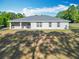 Home's back exterior showcasing ample yard space and a covered patio at 9525 Sw 200 Ct, Dunnellon, FL 34431
