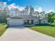 Inviting front exterior with a two-car garage, landscaping, and a welcoming covered porch at 9525 Sw 200 Ct, Dunnellon, FL 34431