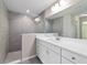 Contemporary bathroom featuring a gray tiled shower, white vanity with a quartz countertop, and stylish lighting fixtures at 10426 Sw 133Rd Ave, Dunnellon, FL 34434