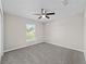 This bedroom features gray carpet, neutral paint and a ceiling fan and window at 10426 Sw 133Rd Ave, Dunnellon, FL 34434