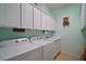Functional laundry room with storage cabinets, washer, dryer, and utility sink for added convenience at 12165 Se 91St Ave, Summerfield, FL 34491