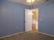Cozy bedroom with light blue walls and neutral carpet featuring an open door at 13816 Sw 112Th Ter, Dunnellon, FL 34432