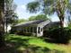 View of the back exterior featuring a sunroom that blends seamlessly into the lush greenery at 14272 Sw 112Th Cir, Dunnellon, FL 34432