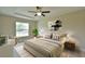 Bedroom with tray ceiling, ceiling fan, neutral walls, and large window overlooking trees at 16219 Sw 48Th Cir, Ocala, FL 34473