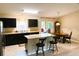 A kitchen featuring dark cabinetry, an island with seating, and a dining area with a grandfather clock at 20386 Sw 95Th St, Dunnellon, FL 34431