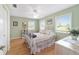Green bedroom with hardwood floors and bright windows offering serene views of the yard at 20921 Sw 36Th St, Dunnellon, FL 34431