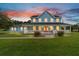 Charming two-story home featuring a welcoming front porch and a beautifully landscaped lawn with a vibrant sunset backdrop at 20921 Sw 36Th St, Dunnellon, FL 34431