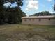 View of a beige home with a metal roof, set on a lot with sparse grass and trees under a partly cloudy sky at 2912 Ne 24Th Ct, Ocala, FL 34479