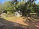 View of backyard shed with green trim, trees, and lawn at 3579 Sw Shorewood Dr, Dunnellon, FL 34431