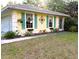 Charming exterior featuring a cheerful yellow facade, complemented by vibrant turquoise shutters and blossoming flower boxes at 3579 Sw Shorewood Dr, Dunnellon, FL 34431