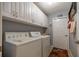 Clean laundry room with overhead storage cabinets, washer, and dryer at 3579 Sw Shorewood Dr, Dunnellon, FL 34431