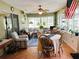Bright living room area with ceiling fan, table set, comfortable furniture, and large windows overlooking the yard at 3579 Sw Shorewood Dr, Dunnellon, FL 34431